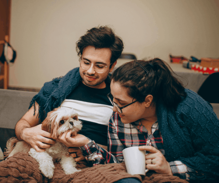 Couple stroking dog on man's lap