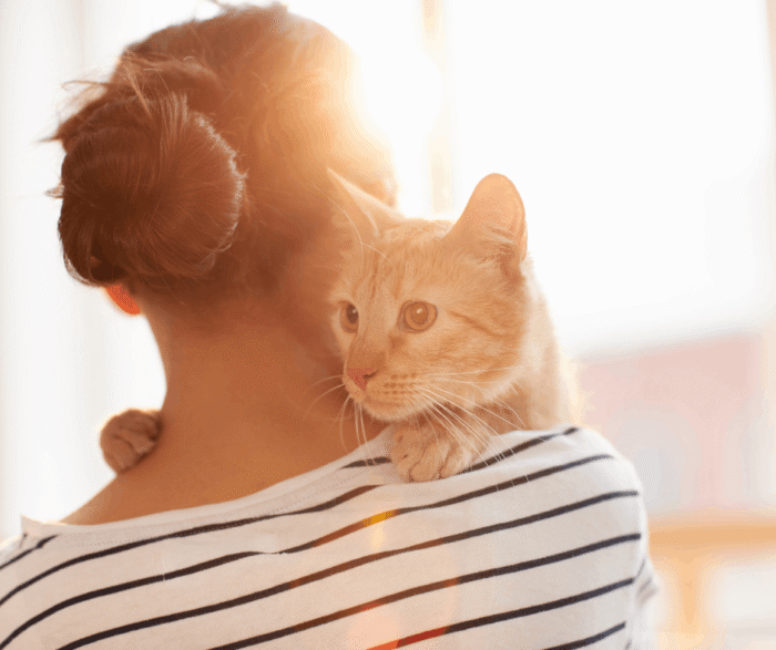 Woman holding cat on her shoulder.